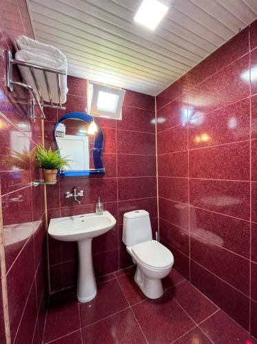 a red tiled bathroom with a toilet and a sink at TA-mari in Ureki
