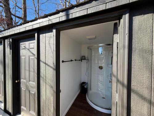 a bathroom with a glass door and a shower at Red River Gorge Creekside Cabin, Hot Tub, Shared Bathhouse in Stanton