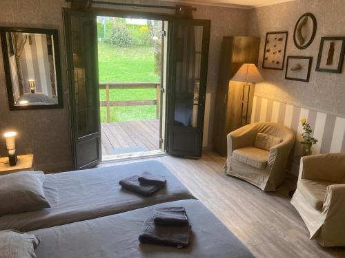 a bedroom with a bed and a chair and a window at La Chêneraie Chambres d'hôtes-B&B in Payrac