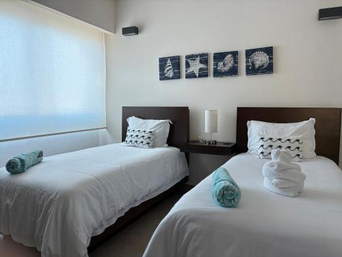 a bedroom with two beds with towels on them at La Poza Condominio in Isla Mujeres