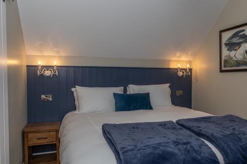 a bedroom with a large bed with a blue headboard at Narrow Water Lodges in Cornamucklagh