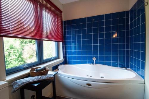 a blue tiled bathroom with a tub and a window at Suardal Guest House in Fort Augustus