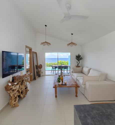 a white living room with a couch and a table at Villa Aura in Oyster Pond