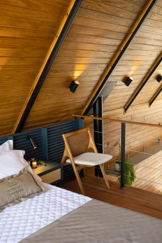 a bed and a chair in a room with wooden ceilings at Cabanas Horizonte Cambará Solare in Cambará