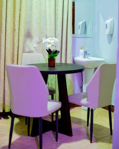 a table with two chairs and a table with flowers on it at JIV Luxury Homes in Mwanza