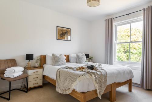 a white bedroom with a bed and a window at Talbot Cottage in Lymington