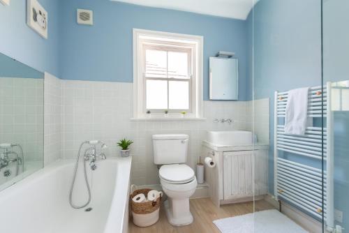 a bathroom with a tub and a toilet and a sink at Talbot Cottage in Lymington