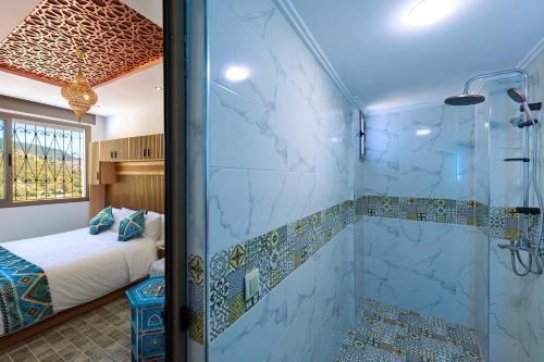 a bathroom with a glass shower and a bed at Riad Seddiki in Chefchaouen