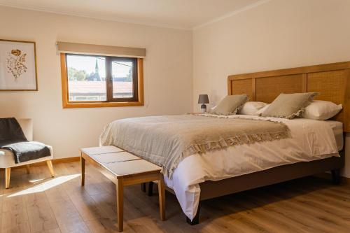 a bedroom with a large bed and a chair at Hotel Los Ríos in Panguipulli