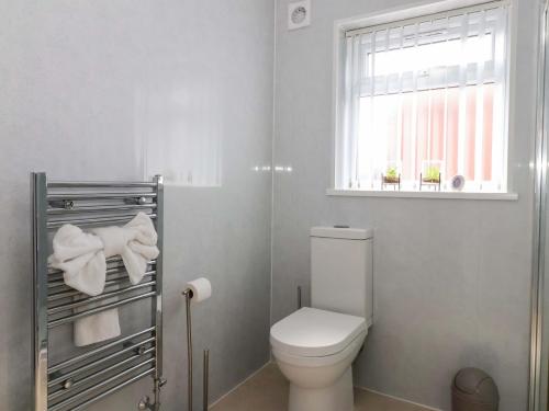 a white bathroom with a toilet and a window at Southview Bungalow in Barmston