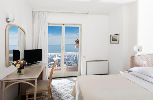 a bedroom with a bed and a desk with a computer at Hotel Club Due Torri in Maiori