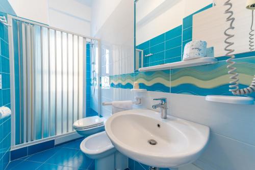 a blue and white bathroom with a sink and a toilet at Hotel Ulisse in Palinuro