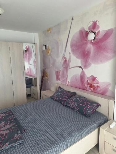 a bedroom with a bed with pink flowers on the wall at Vila Siana in Mamaia