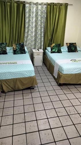 two beds sitting next to each other in a room at Woodbrook on the Avenue in Port-of-Spain
