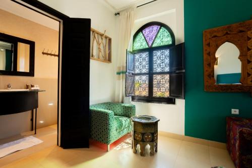 a living room with a chair and a window at Riad Zinaida in Aït Bou Zguia
