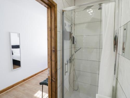 a glass shower door in a bathroom with a chair at JMG House in West Bromwich