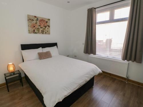 a bedroom with a large white bed with a window at JMG House in West Bromwich