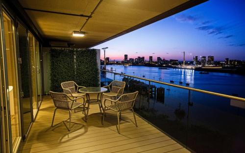 a balcony with a table and chairs and a view of the city at Waterfront- London Greenwich o2 Arena 2 Bed Flat in London