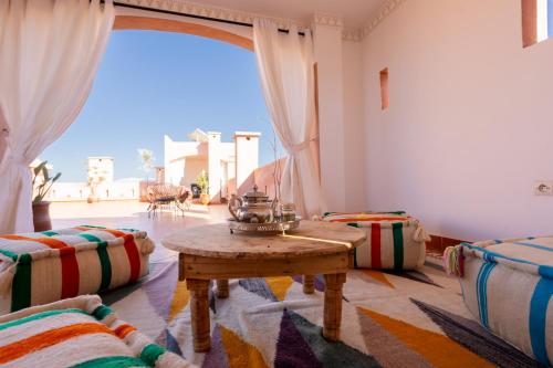a living room with a table and a large window at Riad Zinaida in Aït Bou Zguia