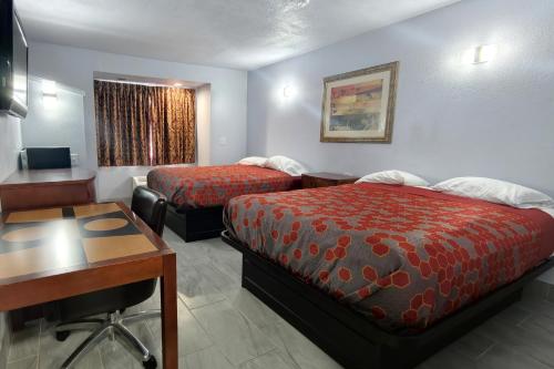 a hotel room with two beds and a desk at Classic Inn San Marcos, TX in San Marcos