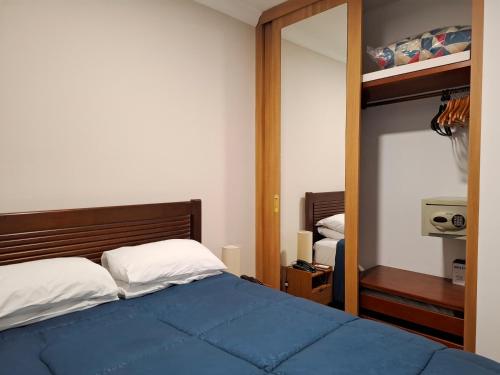 a bedroom with a blue bed and a mirror at Flat IMPECAVEL proximo aos Shoppings JK e Vila Olimpia in São Paulo