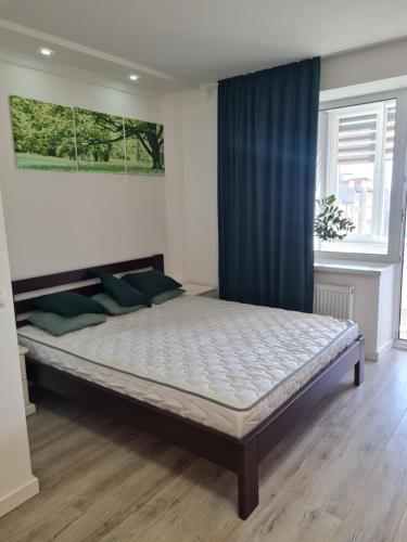 a large bed in a bedroom with a blue curtain at Апартаменти Центр in Lutsk