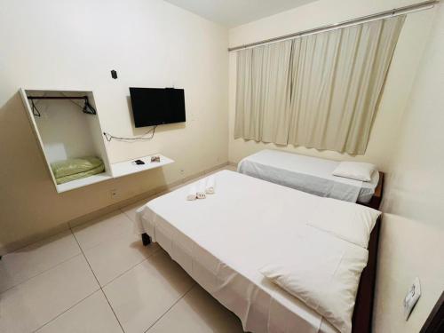 a hotel room with two beds and a mirror at Pousada da Praça in Ponte Alta do Tocantins