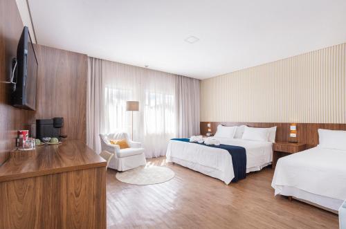 a hotel room with two beds and a television at Hotel Chateau in Campos do Jordão