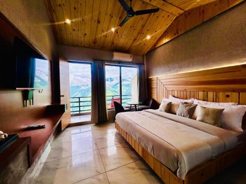 a bedroom with a large bed and large windows at Living On The Edge A Luxury Stay in Mussoorie in Mussoorie