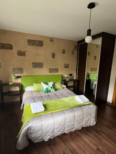 a bedroom with a large bed with a green headboard at La Sabelona in Otero de Sanabria