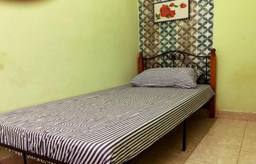 a bed in a room with a striped bedsheet at Dayang Homestay in Kuantan