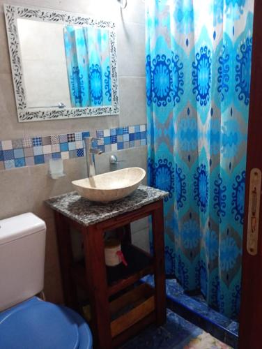 a bathroom with a sink and a blue shower curtain at La esquina amarilla in San Clemente del Tuyú