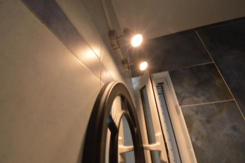 a bathroom with a mirror and lights on the wall at Demetrius's Penthouse in Chalkida