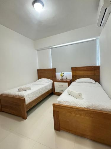 two twin beds in a room with white walls at residencial enmanuel 1 in Hoya del Caimito