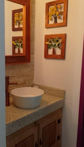 a bathroom with a sink and two pictures on the wall at Pouso Elohim in Tiradentes