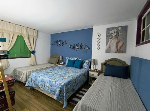 a bedroom with two beds and blue walls at Pouso Elohim in Tiradentes
