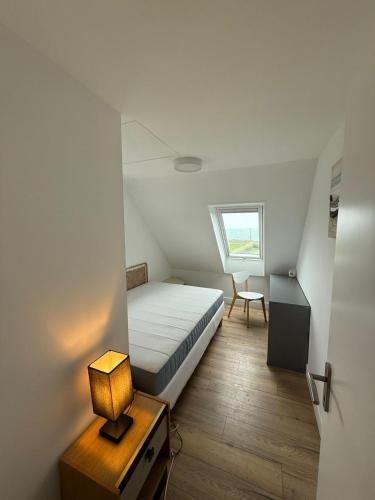 a small bedroom with a bed and a table with a lamp at Maison d'exception face à l'océan in Lampaul-Plouarzel