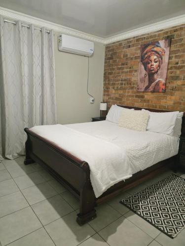 a bed in a room with a brick wall at Vista Ree Guesthouse Pty Ltd in Taung