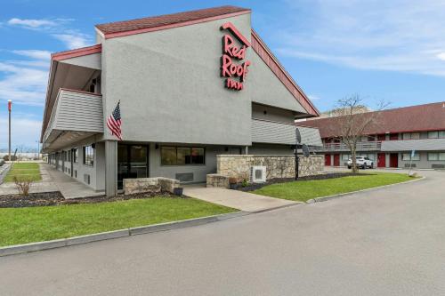 a red rock inn building with an american flag at Red Roof Inn Dayton North Airport in Dayton