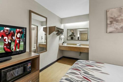 a hotel room with a television and a bathroom at Red Roof Inn Dayton North Airport in Dayton