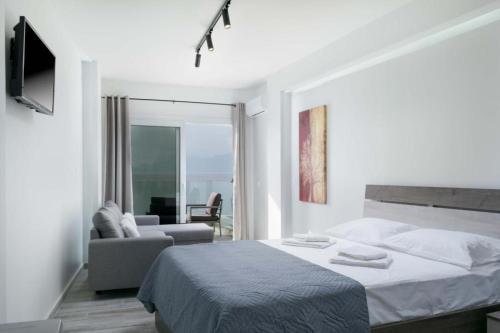 a white bedroom with a bed and a couch at Thalassoresort UPSTAIRS in Matala