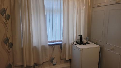 ein Badezimmer mit Fenster und weißem Vorhang in der Unterkunft Ansty Friendly in Wyken