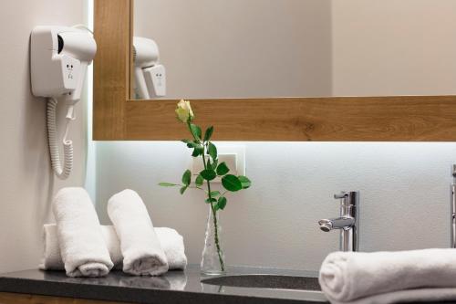 een badkamer met een wastafel met handdoeken en een vaas met een bloem bij Art Hotel's Sosnowiec in Sosnowiec
