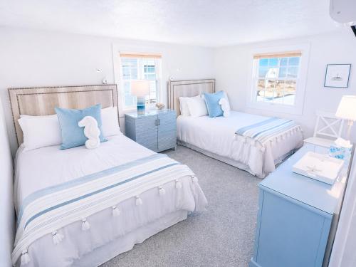 two beds in a bedroom with blue and white at Stunning Bay Views | Beach Access - Deck - Parking in Provincetown