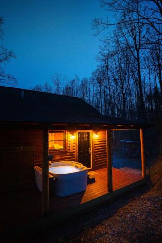 a large bath tub on a wooden deck at night at Secluded Cozy Log Cabin Villa in Creola