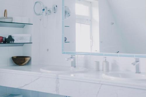 a white bathroom with two sinks and a mirror at Friesenpark 8 in Wurster Nordseeküste