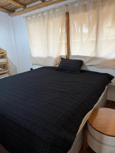 a bedroom with a black bed with a window at Casa verde in Vichayito