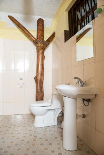 a bathroom with a toilet and a cross on the wall at Kyaninga Royal Cottage in Fort Portal