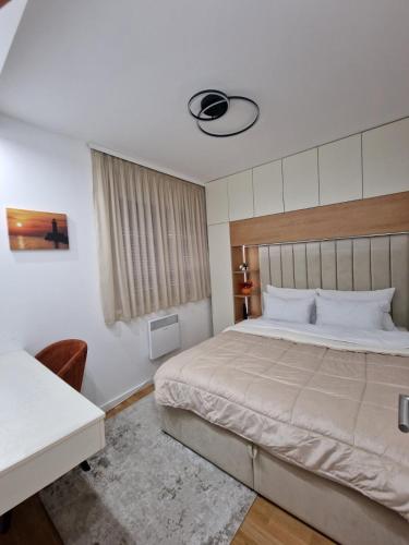 a bedroom with a large bed and a desk at Altura Garden 1 in Vrnjačka Banja