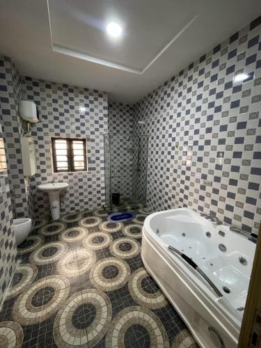 a bathroom with a tub and a tiled floor at Goshen in Iju Junction